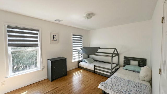 bedroom featuring baseboards, visible vents, and wood finished floors