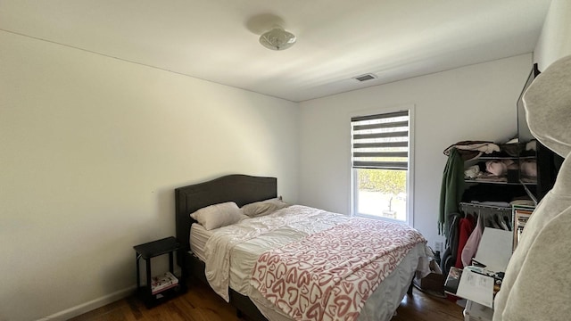 bedroom with dark wood-style floors, visible vents, and baseboards
