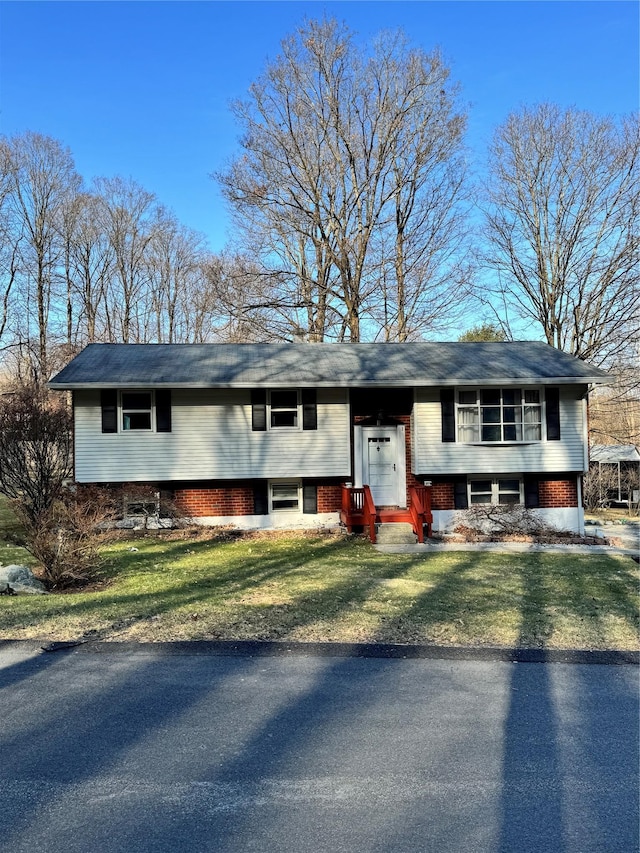 bi-level home with brick siding and a front yard