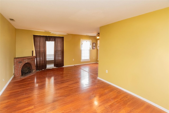 unfurnished living room featuring ceiling fan, hardwood / wood-style floors, and a brick fireplace