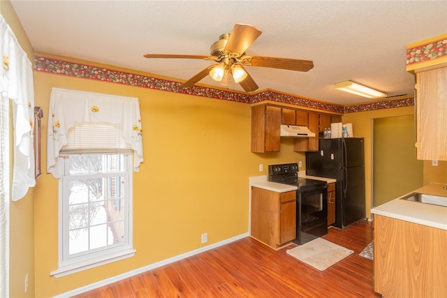 kitchen featuring ceiling fan, sink, light wood-type flooring, and black appliances