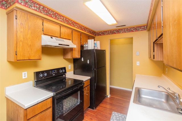 kitchen with hardwood / wood-style flooring, sink, and black appliances