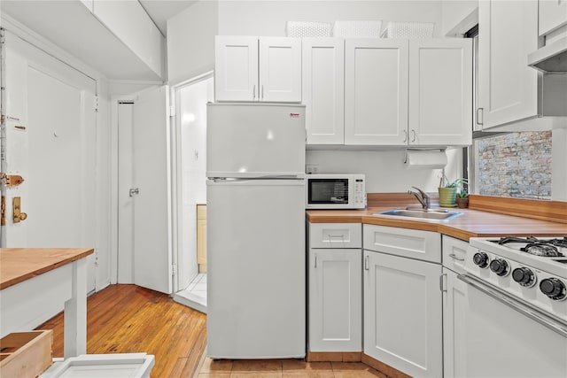 kitchen featuring white cabinetry, white appliances, and range hood