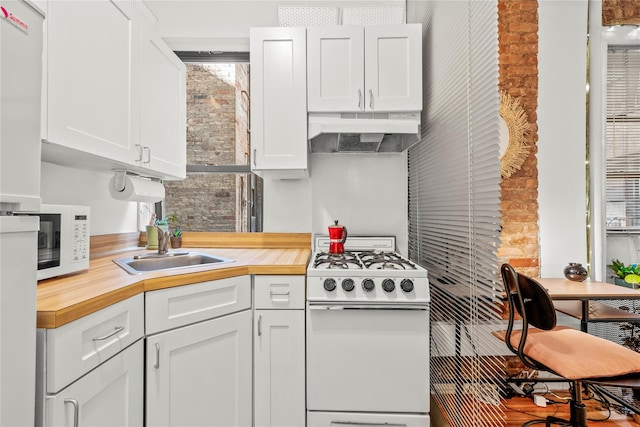 kitchen with brick wall, white cabinetry, sink, butcher block counters, and white appliances