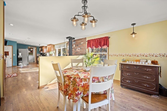 dining area with an inviting chandelier, light hardwood / wood-style flooring, and a wood stove