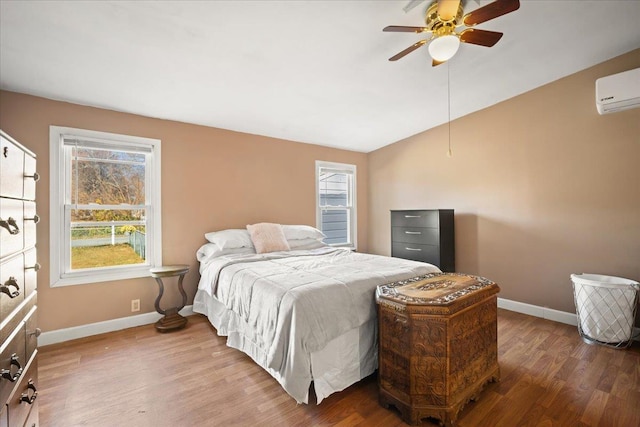 bedroom with hardwood / wood-style flooring, vaulted ceiling, an AC wall unit, and ceiling fan