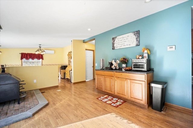 interior space featuring vaulted ceiling, light hardwood / wood-style floors, a chandelier, and a wood stove