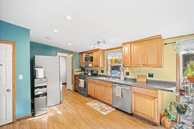 kitchen with lofted ceiling, light brown cabinetry, sink, light hardwood / wood-style flooring, and stainless steel appliances