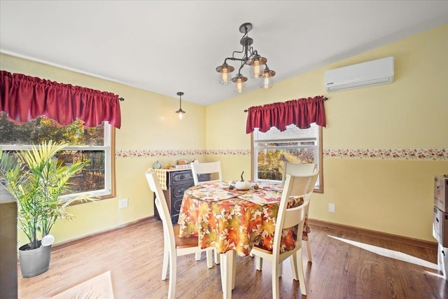 dining room with hardwood / wood-style floors, a notable chandelier, and an AC wall unit