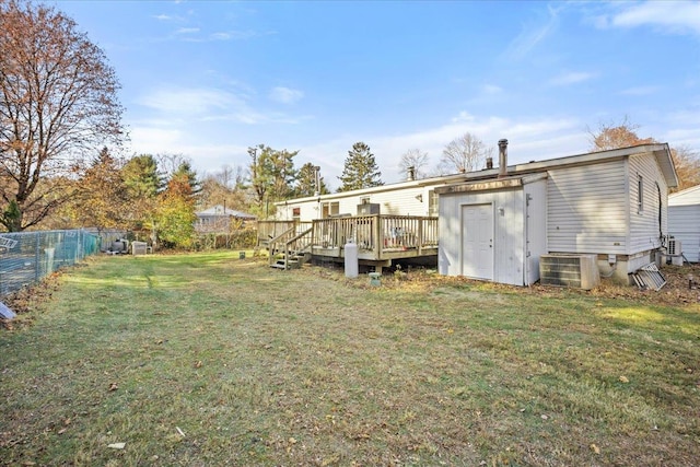 rear view of property featuring a wooden deck and a lawn