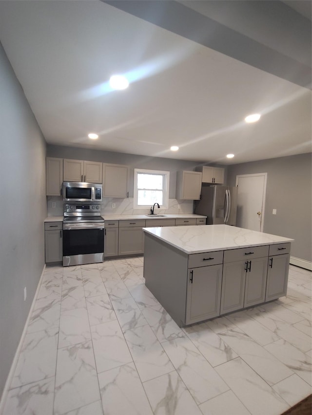 kitchen featuring stainless steel appliances, a center island, light stone countertops, and gray cabinets