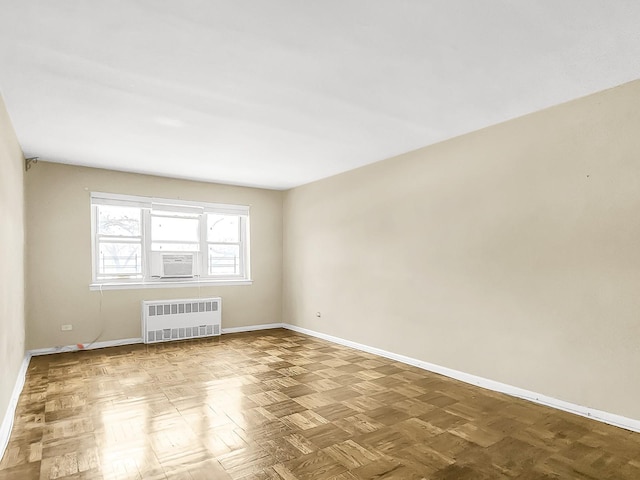 unfurnished room with cooling unit, radiator, and parquet floors