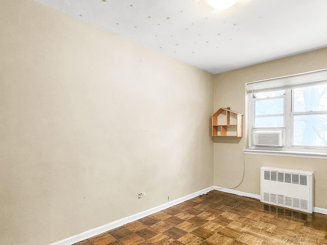 empty room with cooling unit, radiator, and dark parquet floors