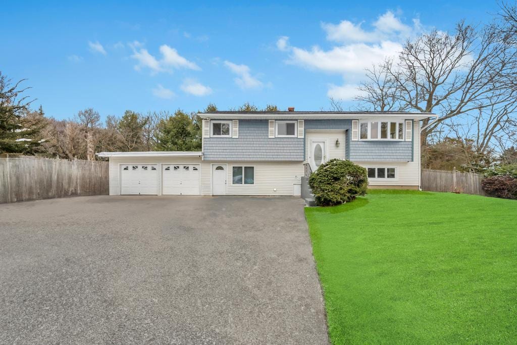 bi-level home featuring a garage and a front lawn