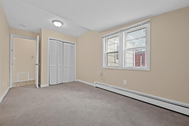 unfurnished bedroom with a baseboard heating unit, light colored carpet, and a closet