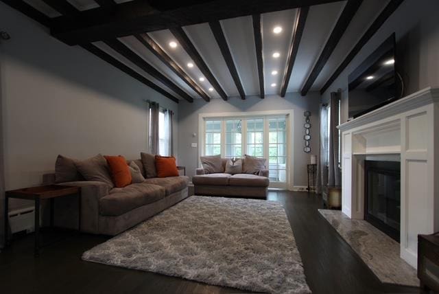 living area featuring a baseboard radiator, recessed lighting, dark wood-type flooring, a fireplace, and beam ceiling