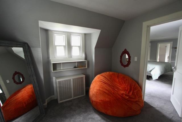 living area with lofted ceiling, dark carpet, and radiator heating unit