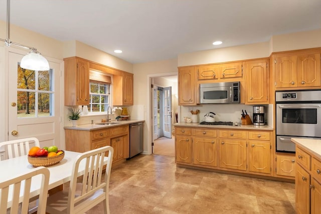 kitchen featuring appliances with stainless steel finishes, sink, and decorative light fixtures