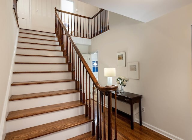 stairs featuring wood-type flooring and a high ceiling