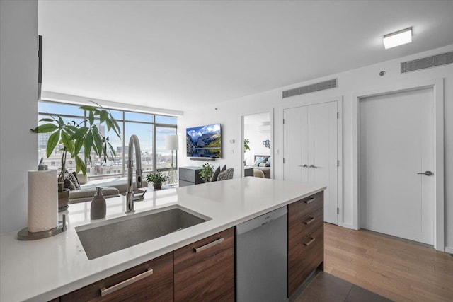 kitchen with dark brown cabinetry, sink, stainless steel dishwasher, and dark hardwood / wood-style floors