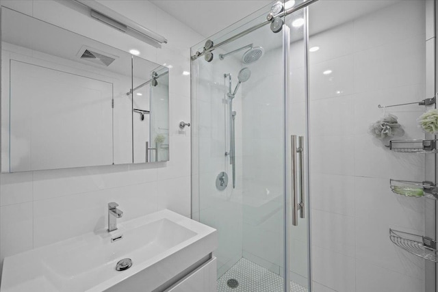 bathroom with vanity, tile walls, and an enclosed shower