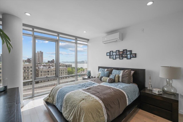 bedroom with a wall of windows, a wall unit AC, and wood-type flooring