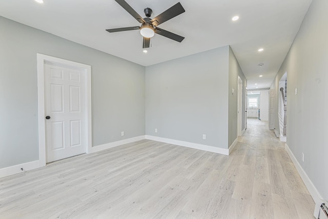 empty room featuring baseboard heating, ceiling fan, and light hardwood / wood-style floors