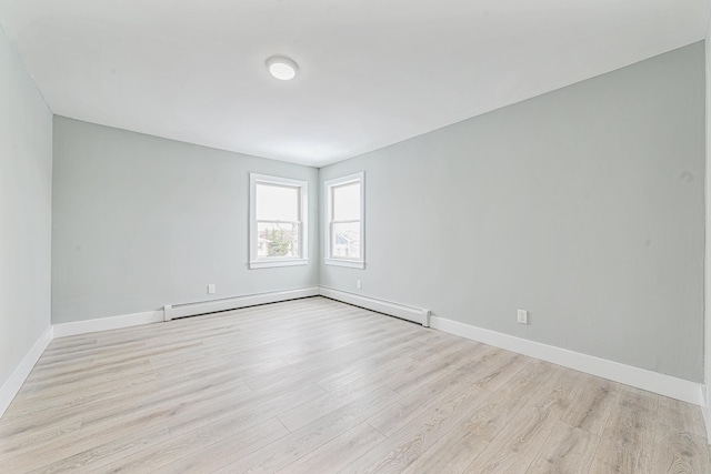 unfurnished room featuring a baseboard heating unit and light hardwood / wood-style flooring