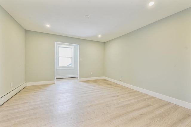 unfurnished room featuring a baseboard radiator and light wood-type flooring