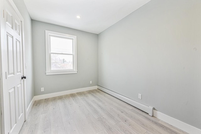 unfurnished room with a baseboard radiator and light wood-type flooring