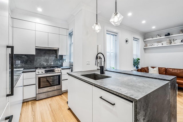 kitchen with sink, gas range, decorative light fixtures, a kitchen island with sink, and white cabinets