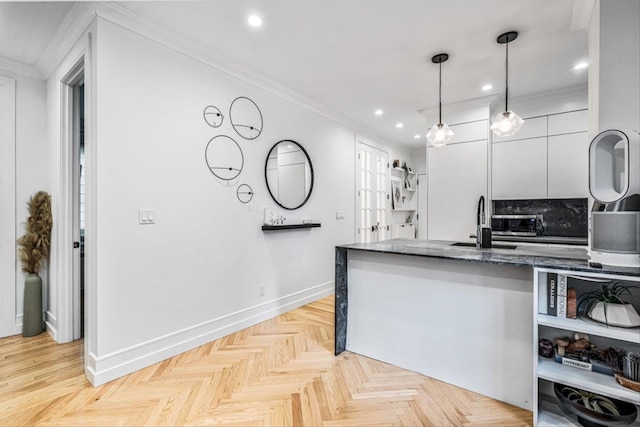 kitchen featuring hanging light fixtures, light parquet flooring, ornamental molding, and white cabinets