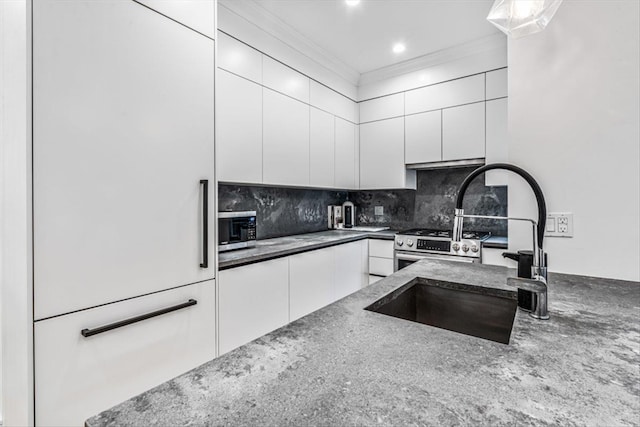 kitchen featuring crown molding, white cabinetry, backsplash, dark stone countertops, and stainless steel appliances