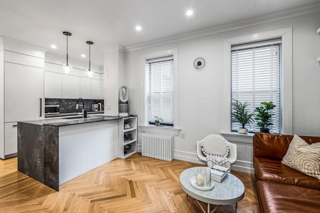 kitchen with white cabinetry, pendant lighting, sink, and radiator heating unit