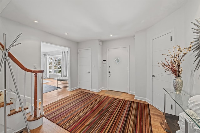 foyer entrance with light wood-style floors, stairs, baseboards, and recessed lighting