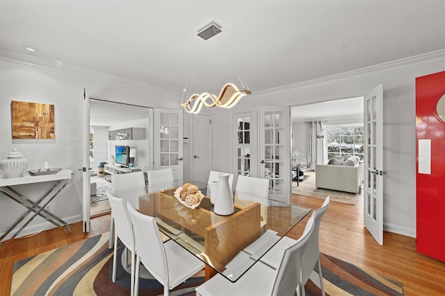 dining space with ornamental molding, french doors, light wood finished floors, and baseboards