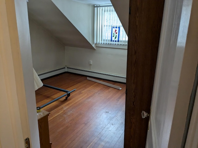 additional living space with a baseboard heating unit and wood-type flooring