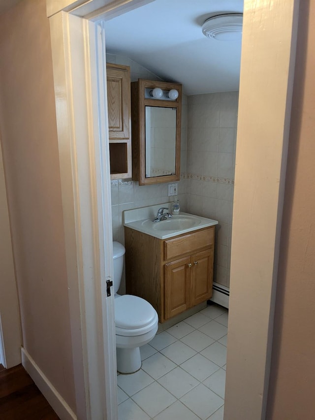 bathroom featuring tile patterned floors, toilet, vanity, a baseboard heating unit, and tile walls