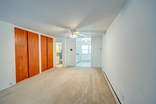 unfurnished bedroom featuring ensuite bath, light colored carpet, multiple closets, and baseboard heating