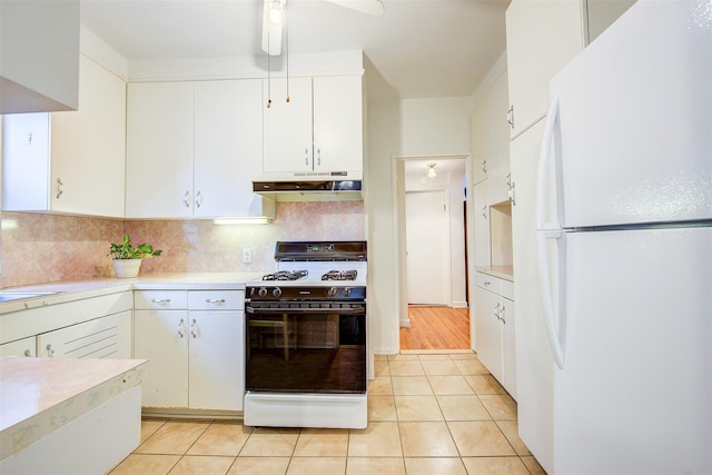 kitchen featuring range with gas cooktop, white cabinetry, backsplash, white refrigerator, and light tile patterned floors