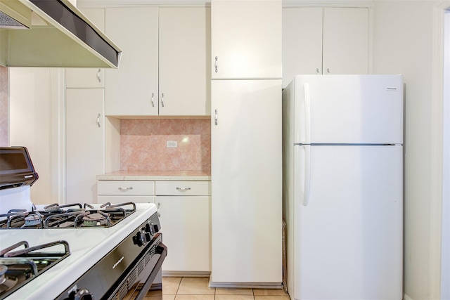 kitchen with white refrigerator, gas stove, exhaust hood, and white cabinets