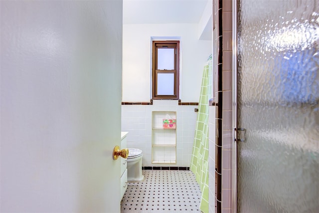 bathroom featuring toilet, tile walls, tile patterned floors, and a shower with shower door