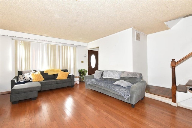 living area featuring stairs, visible vents, a textured ceiling, and hardwood / wood-style flooring