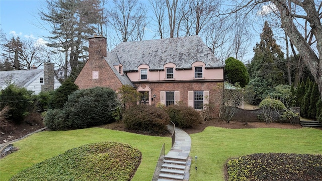 view of front of home with brick siding, a front yard, a chimney, and stucco siding