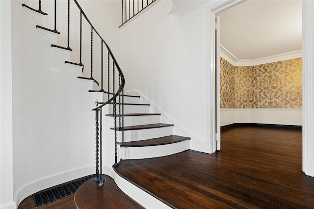 stairway featuring visible vents, ornamental molding, wood finished floors, baseboards, and wallpapered walls