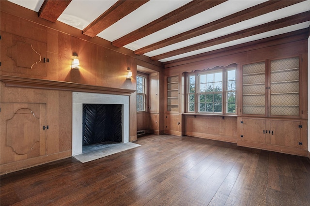 unfurnished living room with beam ceiling, wood walls, hardwood / wood-style flooring, and built in features