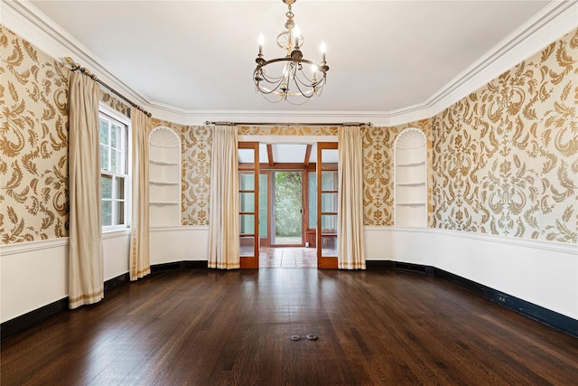 empty room with a wainscoted wall, wood-type flooring, an inviting chandelier, baseboards, and wallpapered walls