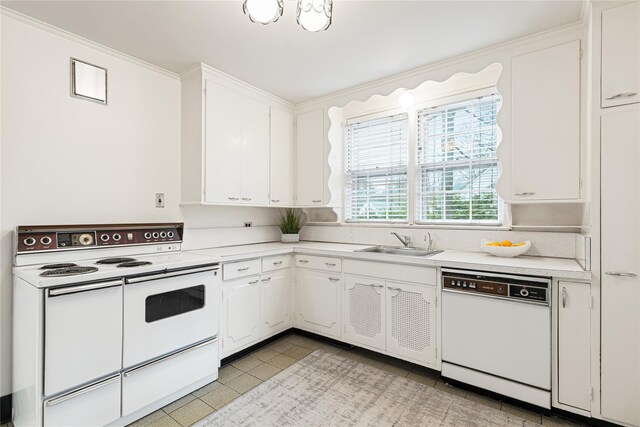 kitchen with white appliances, light countertops, a sink, and white cabinetry