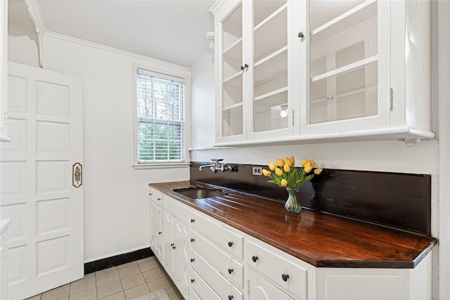 kitchen featuring glass insert cabinets, a sink, and light tile patterned flooring