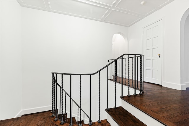 stairway featuring baseboards, arched walkways, and wood finished floors